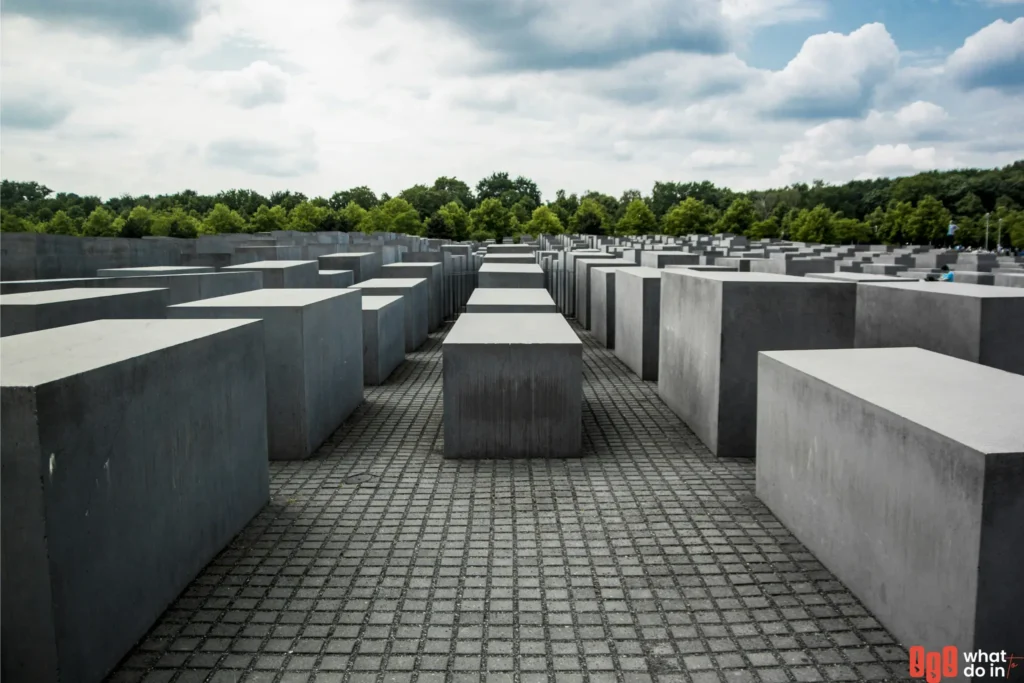Holocaust Memorial in Berlin with rows of concrete slabs under a cloudy sky, symbolizing remembrance and reflection in the heart of Germany’s capital.